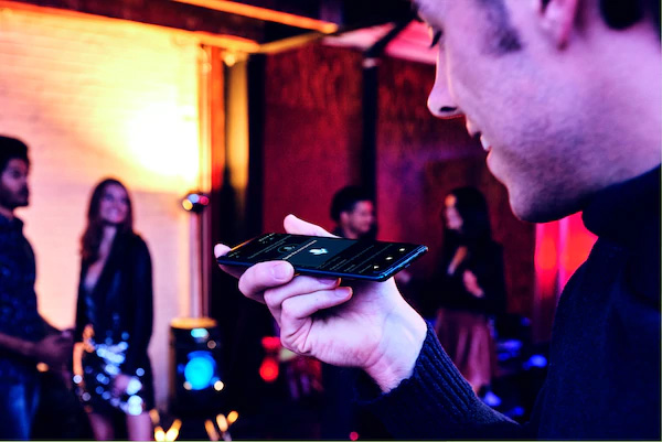 Khách dự tiệc dùng tính năng Điều khiển bằng giọng nói qua ứng dụng Fiestable trên điện thoại thông minh