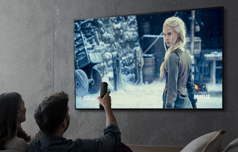 Hình ảnh cho thấy một cặp vợ chồng đang xem một chương trình bằng TV LG UHD.